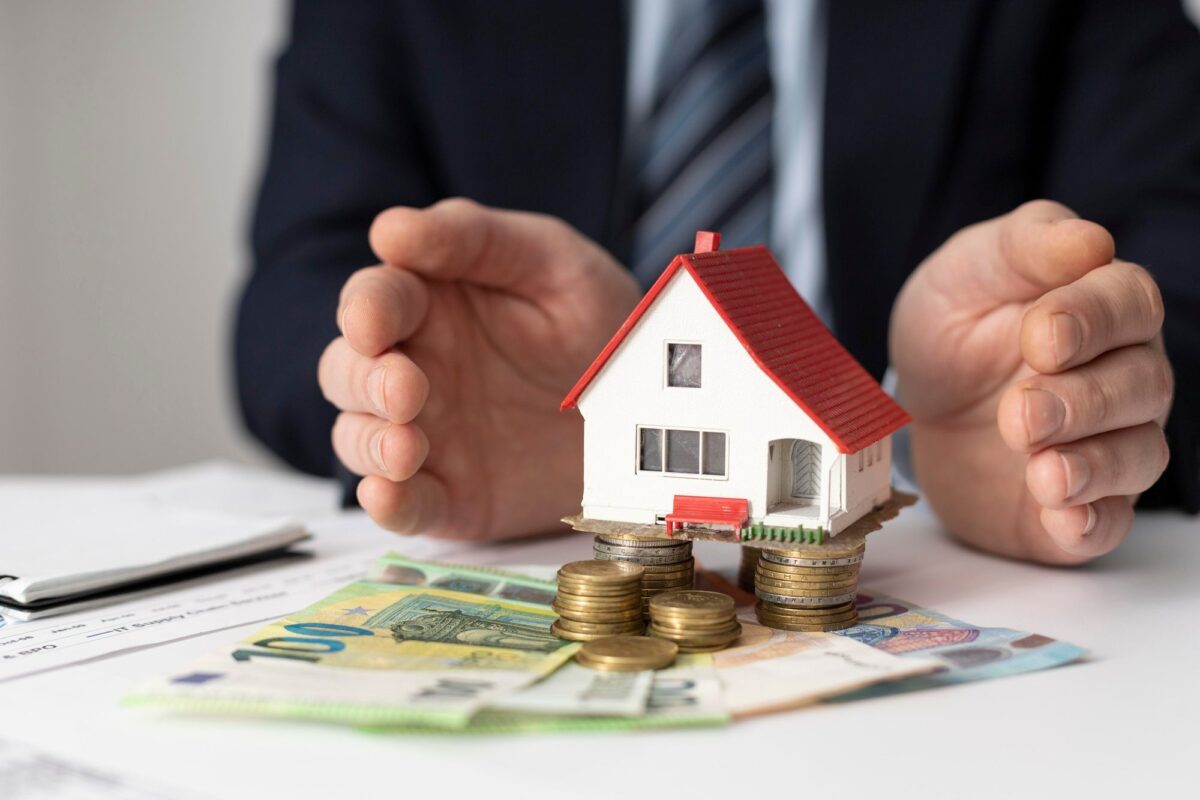 Haus und Geld als Symbole für Blick auf Immobilienpreise