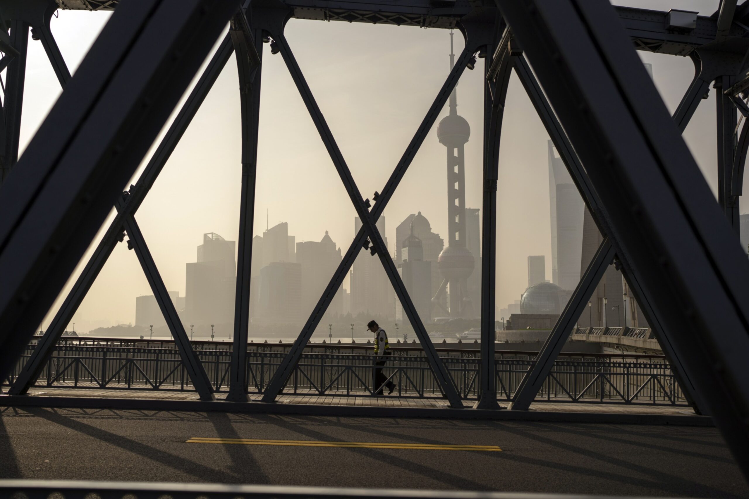 A pedestrian walks across a bridge in front of buildings in Pudong's Lujiazui Financial District in Shanghai, China, on Wednesday, June 21, 2023. China's yuan weakened past the closely watched 7.2-per-dollar level as investor sentiment soured on a lack of aggressive stimulus and Beijing signaled a level of comfort about the declines. Photographer: Raul Ariano/Bloomberg