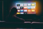 Der Fernseher zeigt Streaming-Apps wie Netflix, YouTube und Apple TV auf einem dunklen Bildschirm.