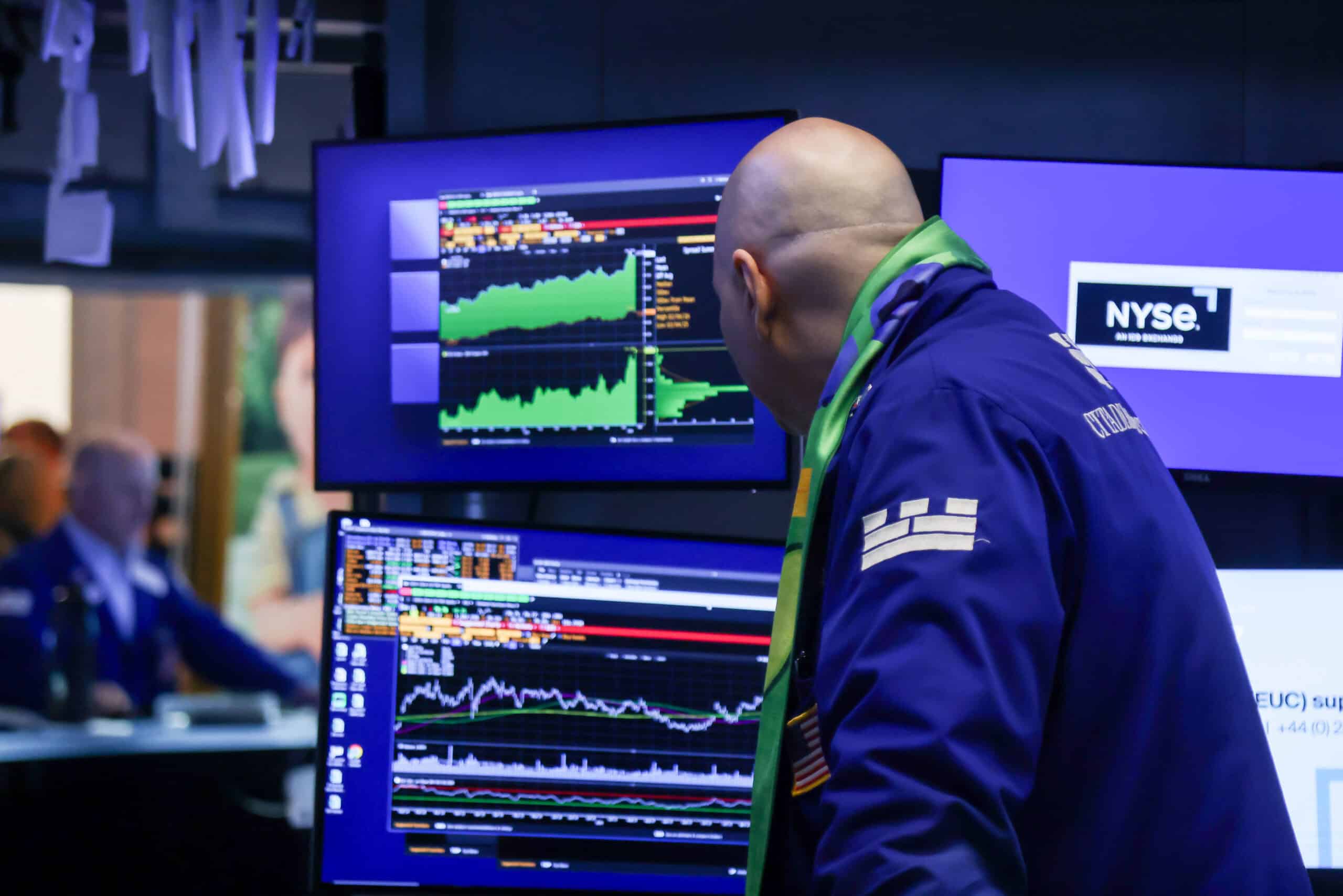 Aktienhändler überwacht Börsenhandel an der NYSE mit mehreren Monitoren.