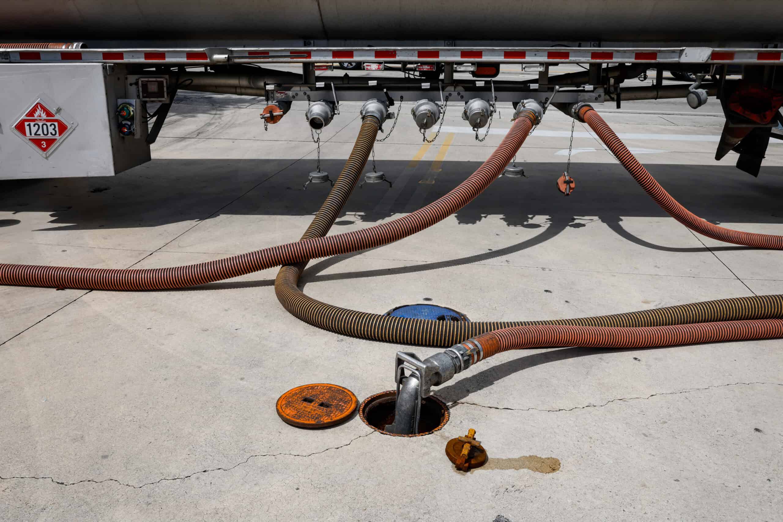 Öltransportleitung an einem Tankwagen, Gefahrgutkennzeichen 1203, auf Asphalt.