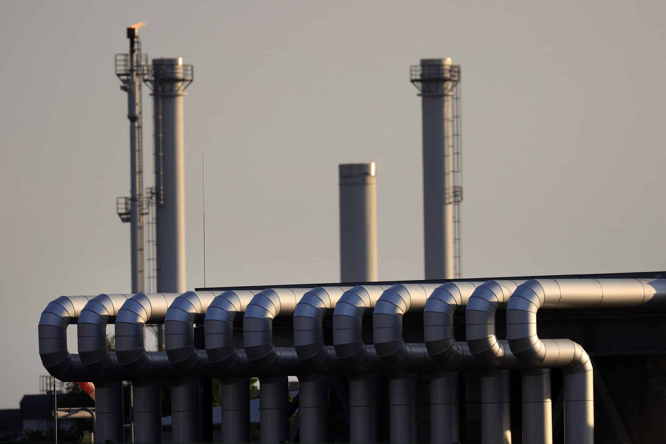 Industrielle Infrastruktur mit Rohren und Schornsteinen bei Sonnenuntergang.