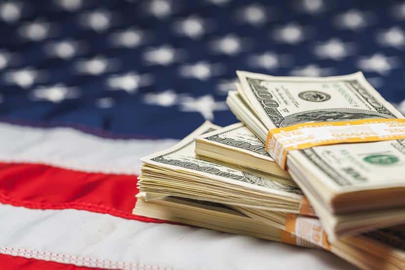 Bündel US-Dollar auf amerikanischer Flagge, Symbol für Finanzmärkte und Wirtschaft.