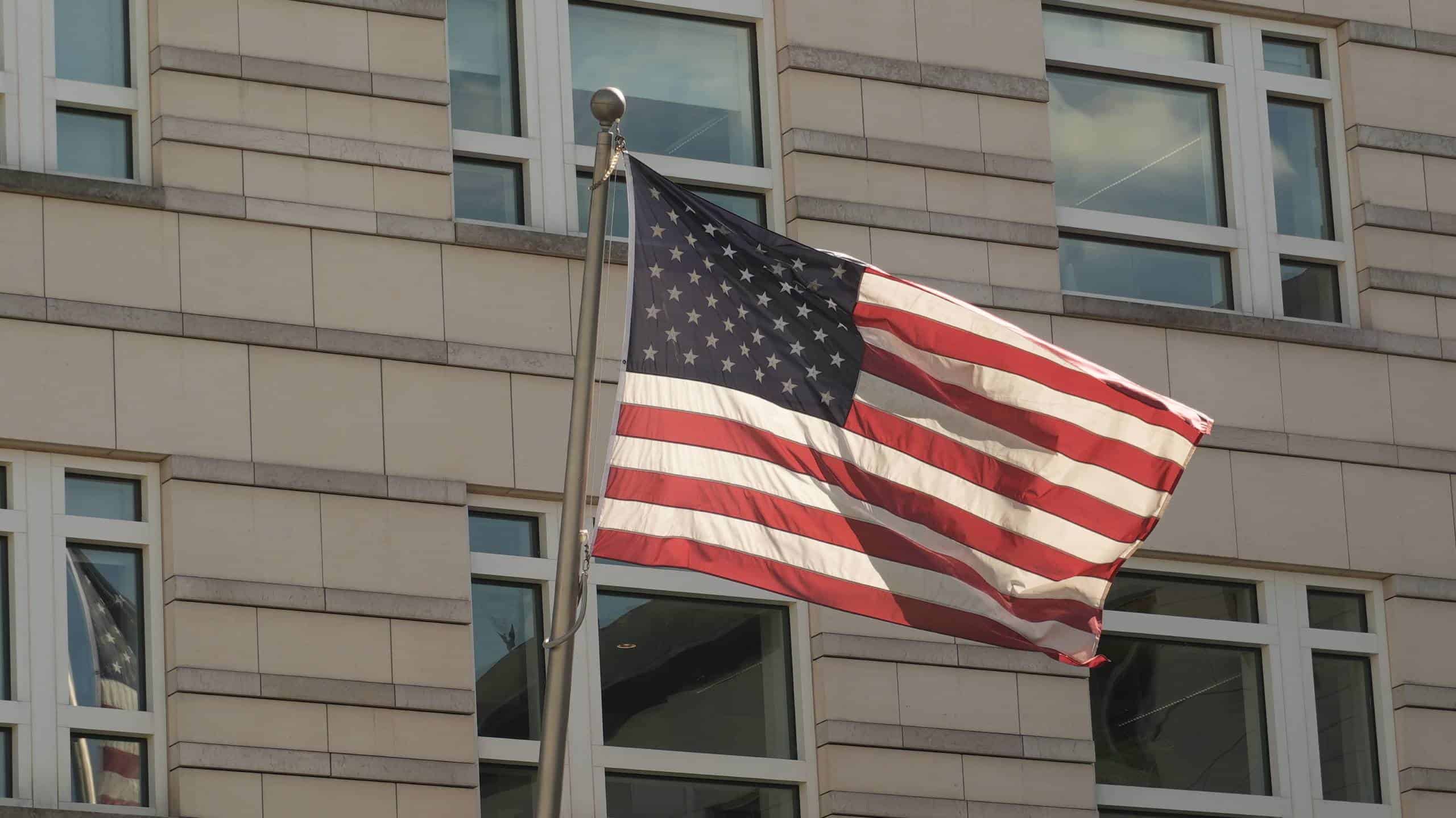 Amerikanische Flagge weht vor einem modernen Bürogebäude.